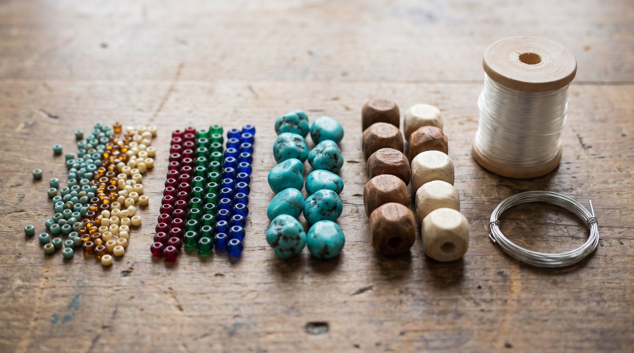 Close-up of different bead sizes and elastic cord on a wooden surface