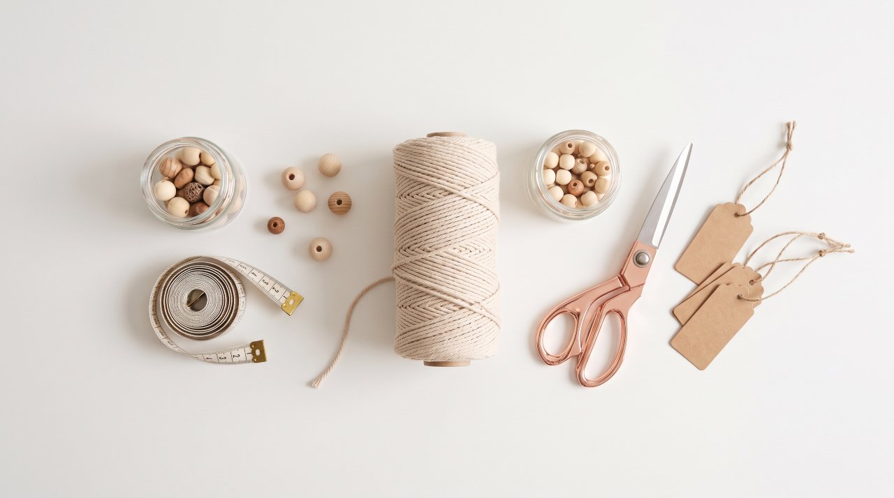 Overhead flat lay of craft supplies with cost labels and measuring tape on white surface
