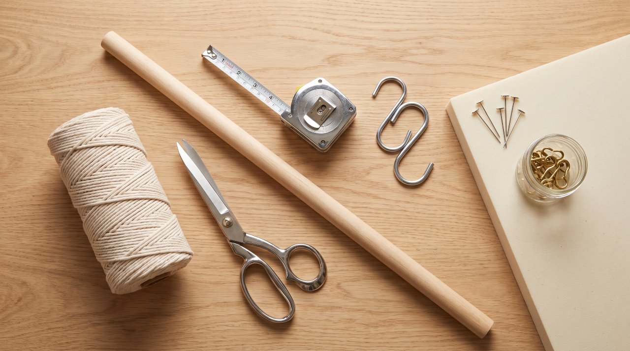 Flat lay of macrame curtain supplies including cord scissors dowel and hooks
