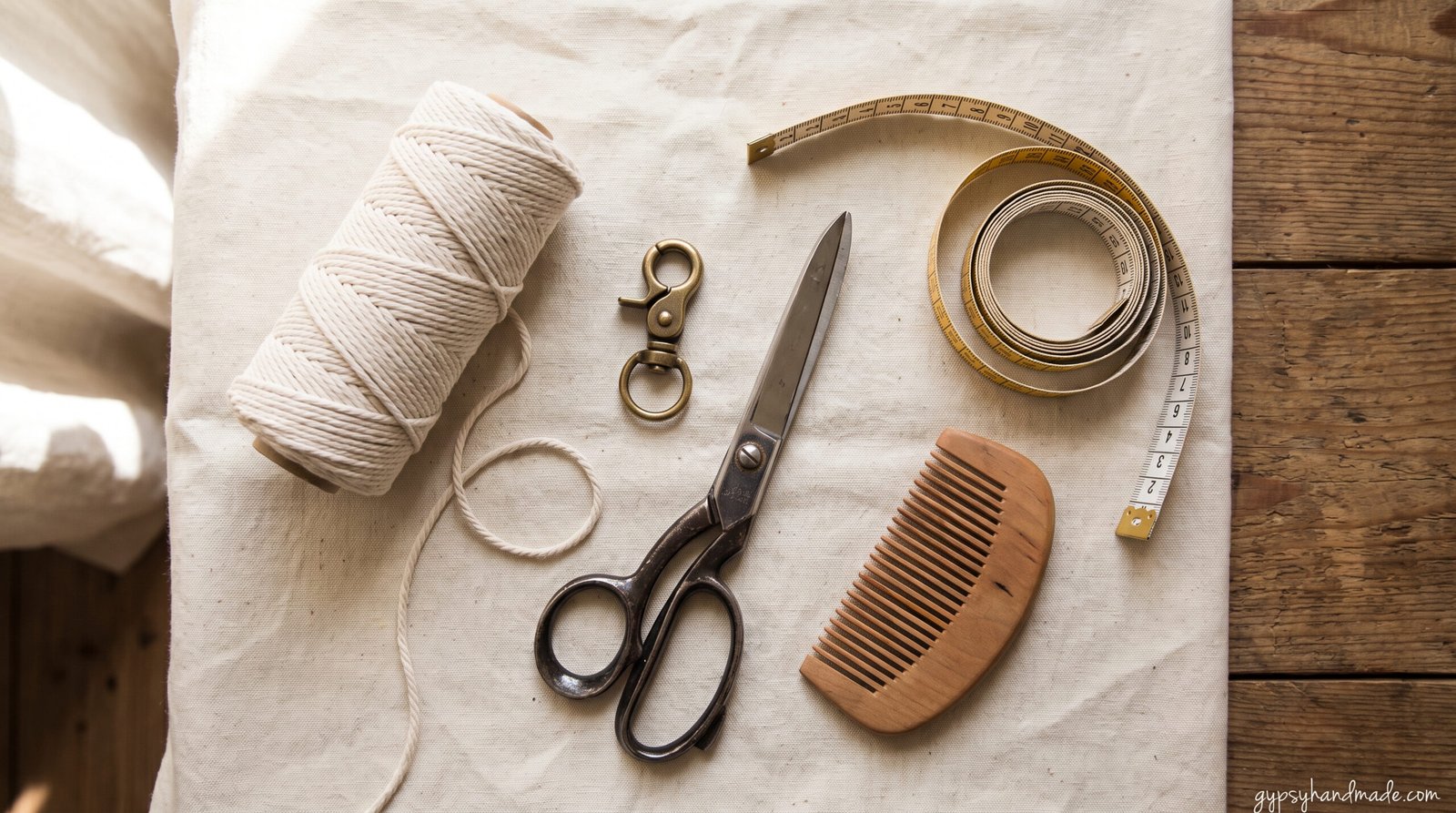 Flat lay of macramé keychain supplies including cotton cord, brass lobster clasp, scissors and measuring tape.